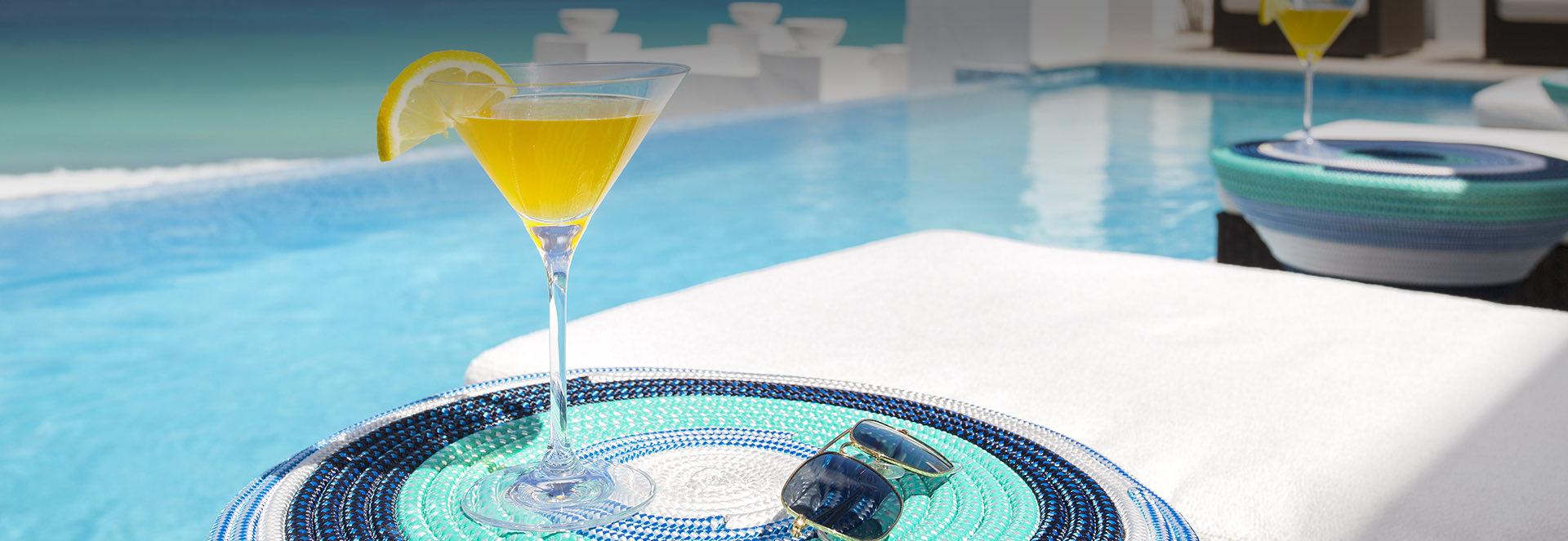 View of a colorful table placemat with a tropical beverage and sun glasses on top