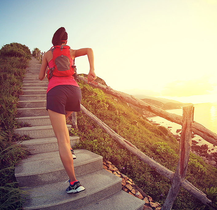 A woman going up stairs outdoors at the sunrise