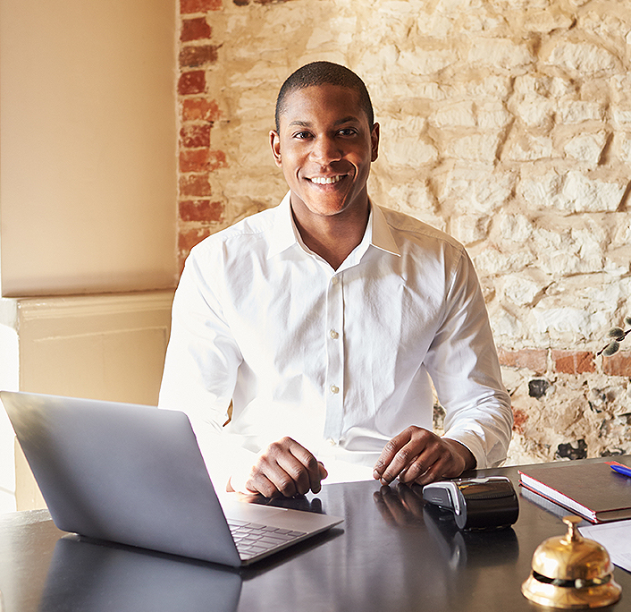 A smiley man looking at the camera with a computer beside him