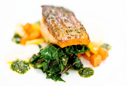 close up view of salmon on a bed of cooked vegetables