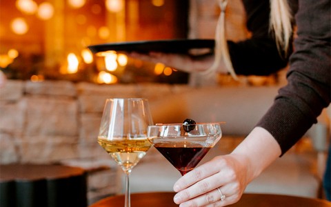 a server setting cocktails down on a small golden table