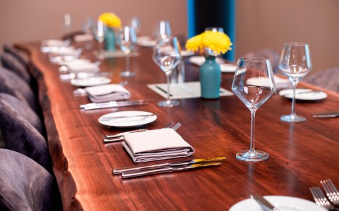 view of wine glasses and place settings on a large wooden table