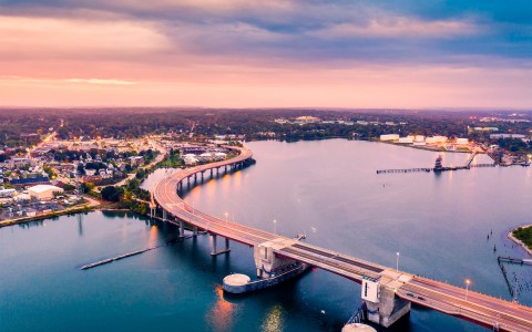 aerial view of a bridge leading to the city of waterville during sunset