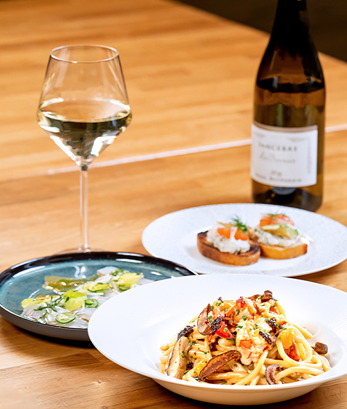 an elegant pasta dish with two side dishes served with white wine