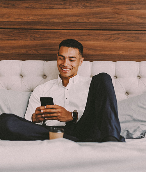 a man sitting on a bed looking at his phone in his hands