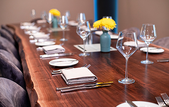 close up view of a wooden table with wine glasses and elegant place settings