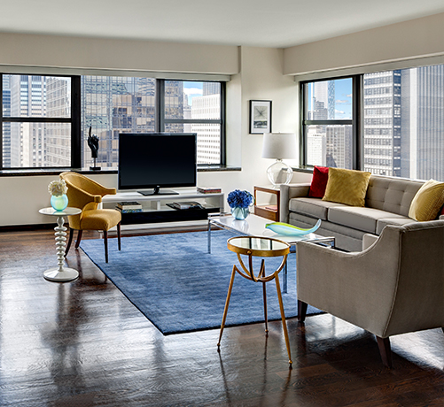 living room view in Metro Suite includes accent chairs and media stand with tv