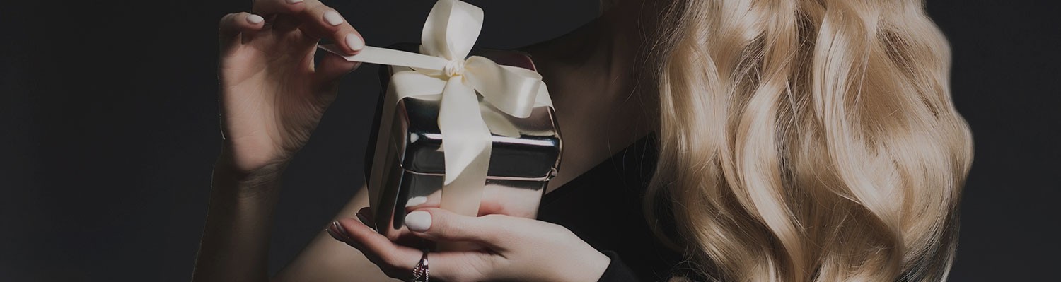 elegant women untying white ribbon on silver giftbox
