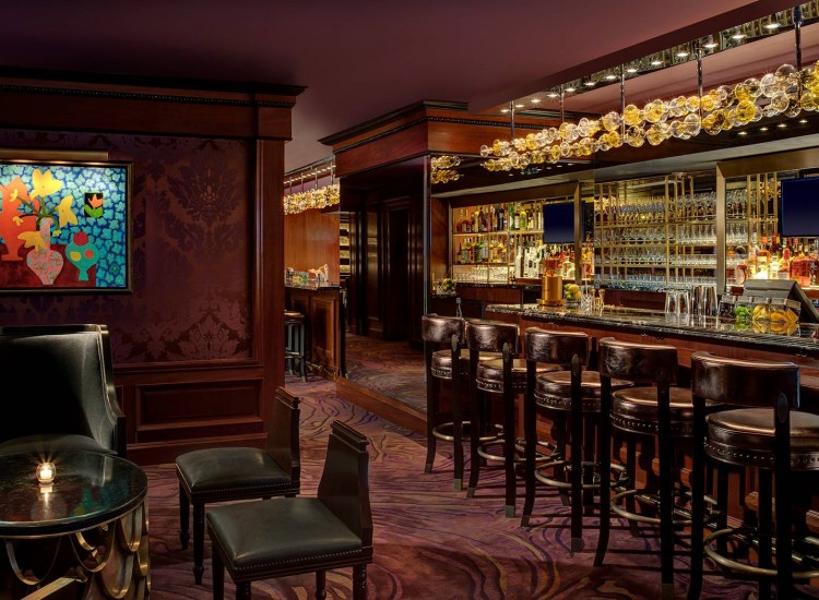 Elegant bar with brown toned walls, wooden accents & leather stools