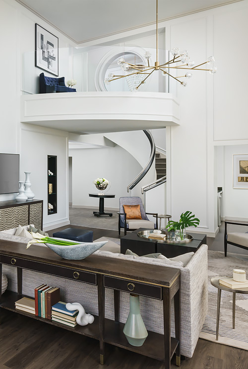 living area with beige couch and stairs leading up to second floor with indoor balcony