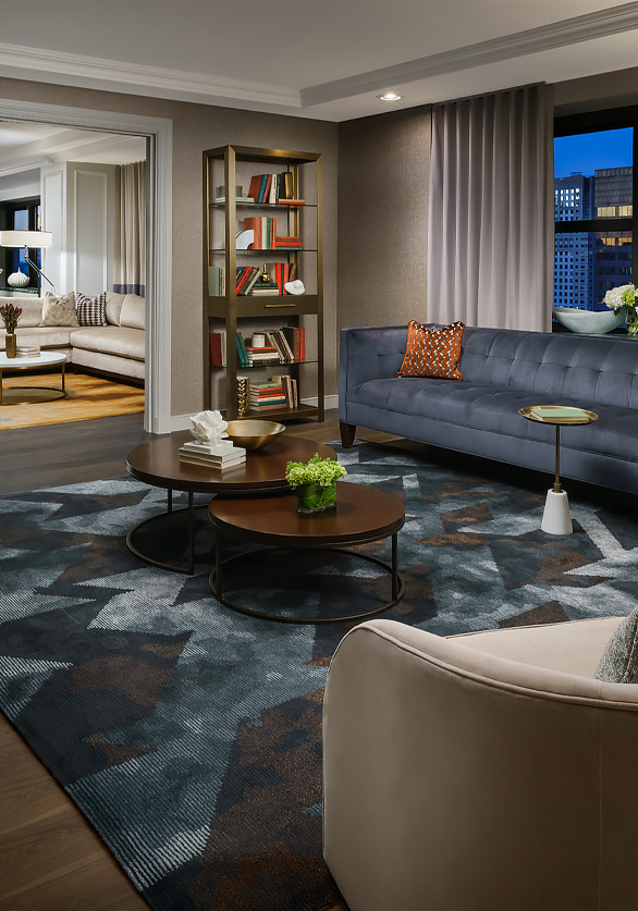 living room of suite with dark blue sofa and round coffee tables on top of a blue and brown abstract rug