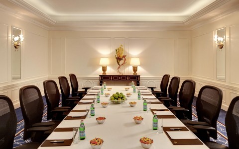 long rectangular table set for board meeting with waters and notes