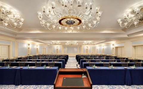 view of rows of tables from the podium with a chandelier above