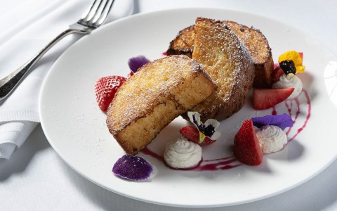 plate with french toast and fruit with whipped cream on a white plate 