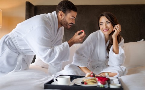 couple in robes having breakfast in bed