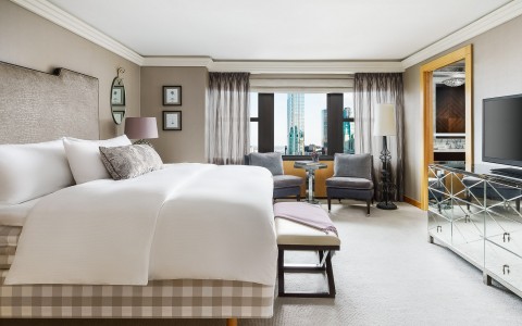 king bed in hotel room with foot bench