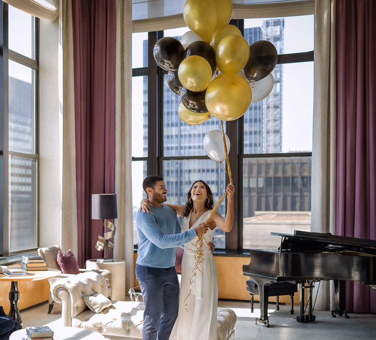 a couple in the towers suite holding gold and black balloons