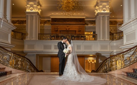 bride and groom embrace at the top of the staircase 