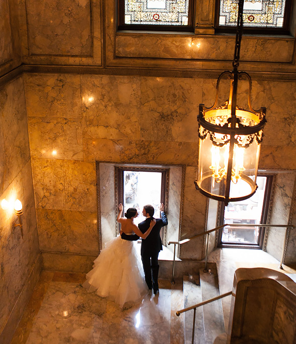 bride and groom looking out of window at villard mansion