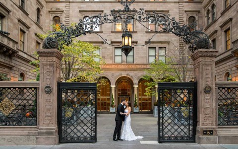 bride and groom kiss at the gates in front of the court yard 