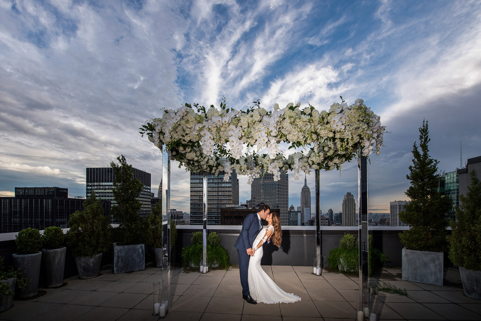 allison and jason kissing on the rooftop patio with the city in the background 