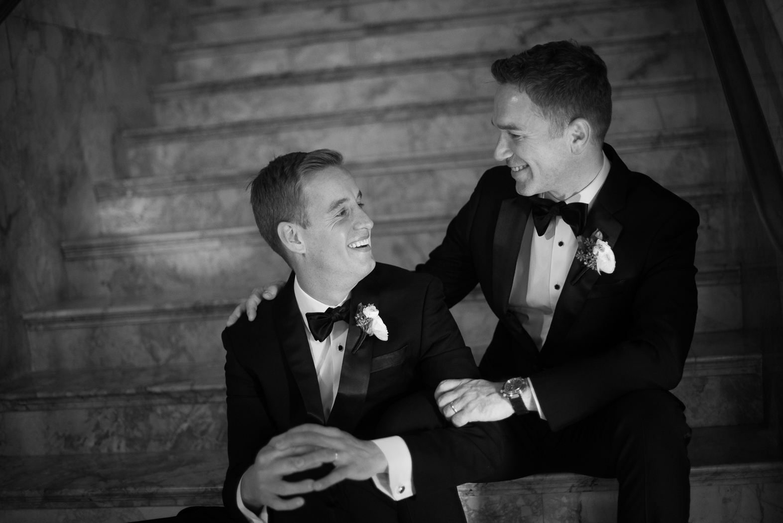 grooms laughing on the stair case 