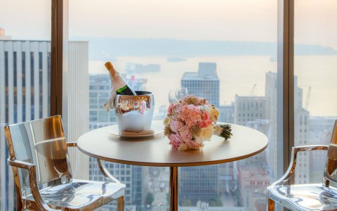 bouquet of flowers and a bottle of chilled champagne on the table with the view of the city in the background