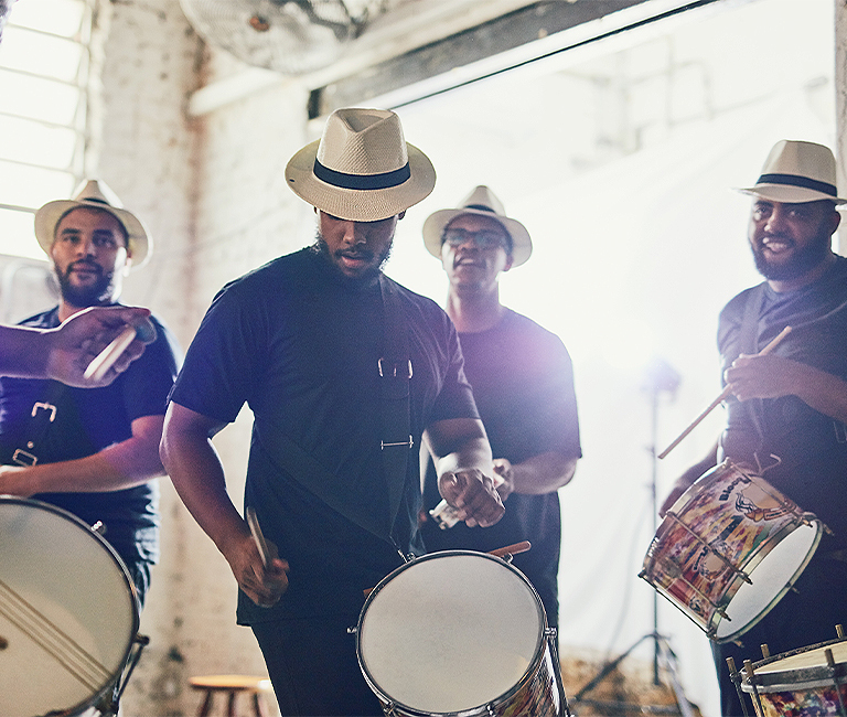 4 men wearing white hats drumming 