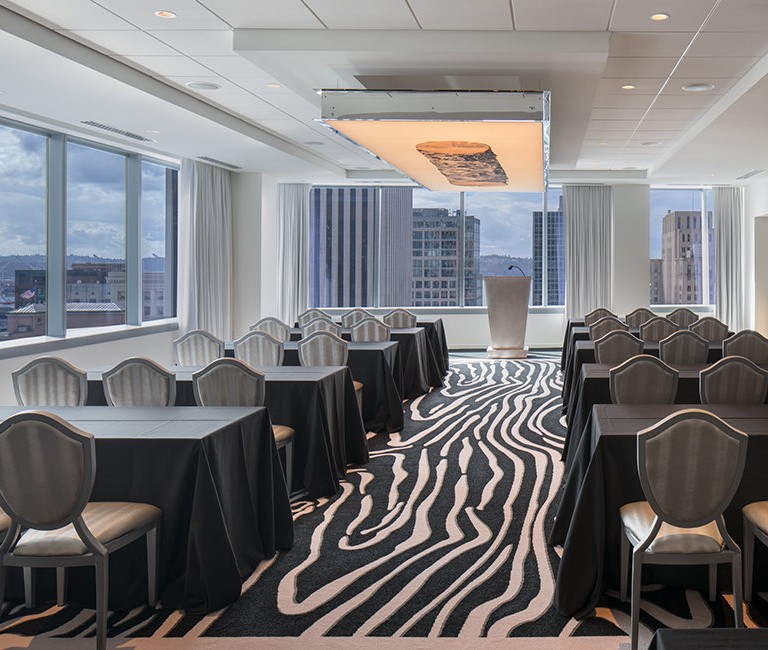 smaller meeting space with table and seats set up and the view of the city at the front of the room