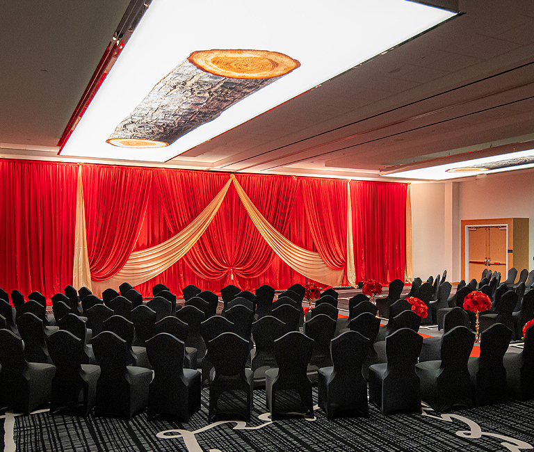 modern ballroom meeting venue, with red drapes hanging on stage and black chairs available
