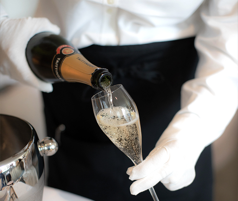 a server pouring champagne into the glass