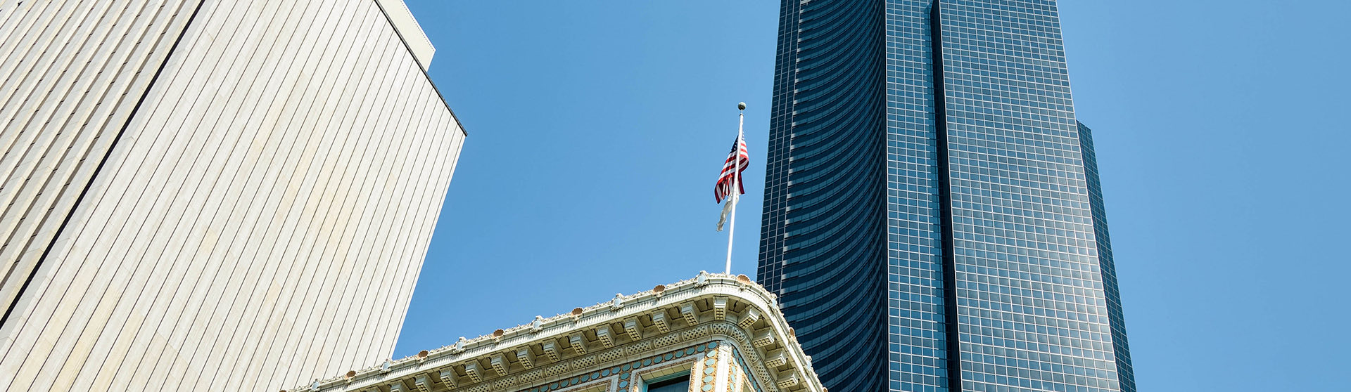 upward shot of american flag and skyscraper