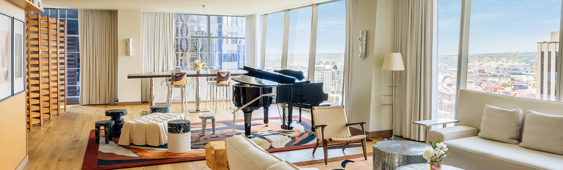presidential suite living area with grand piano in the center and floor to ceiling windows overlooking the city