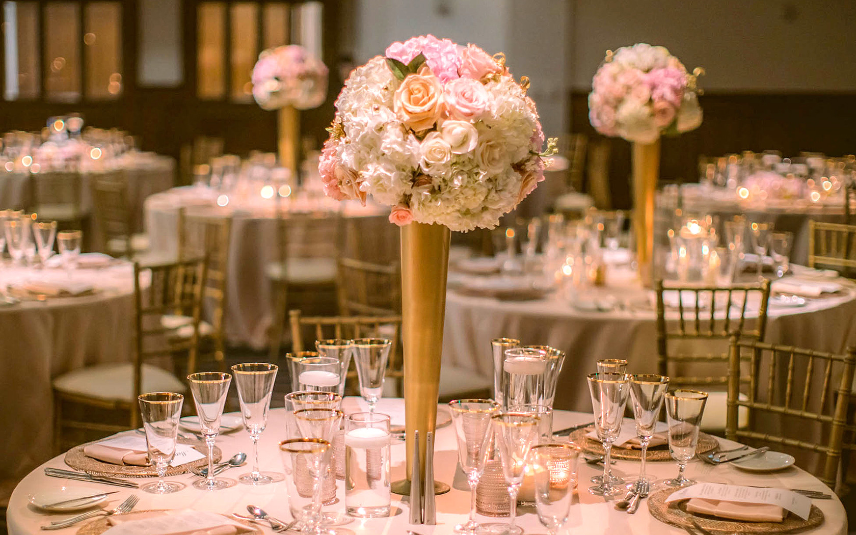 view of a wedding venue table set up with a gold and soft pink color scheme