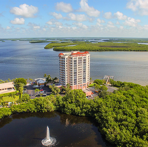 Aerial shot of hotel surrounded by greenery and body of water