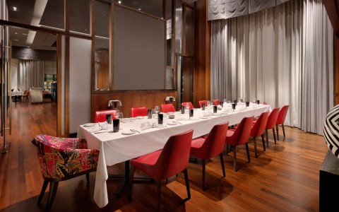 long dining table in a private dining room with red chairs