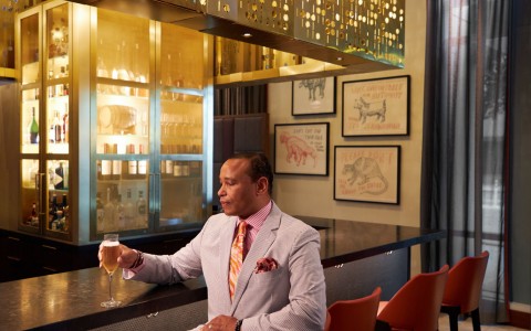 man in a suit holding a drink at a bar
