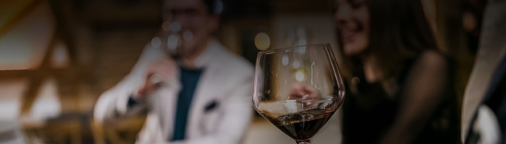 glass of wine with people blurred in background