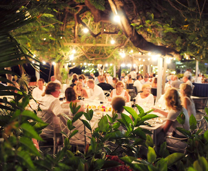 group of people sitting at table outside under string lights