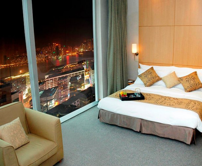 bed with tray on it and floor to ceiling window with view of hong kong at night