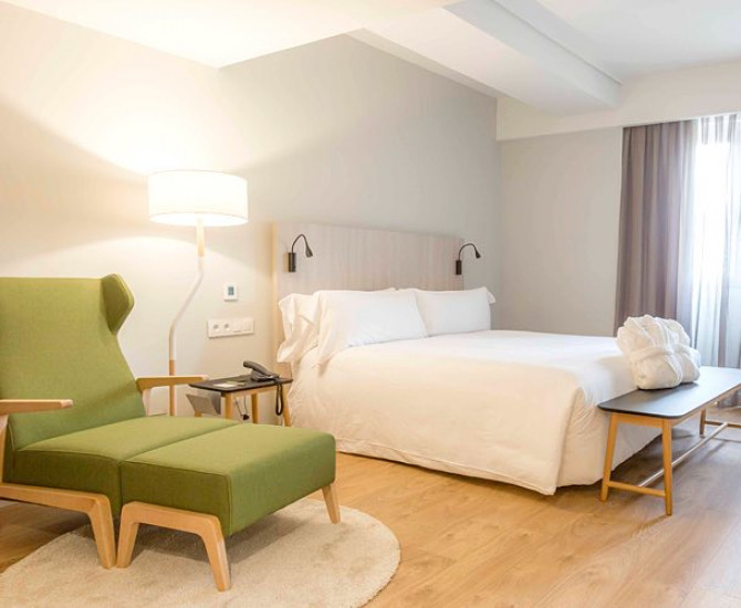 white bed and a green armchair with matching footrest