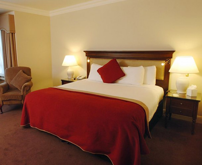Guest room queen bed with white and red linens