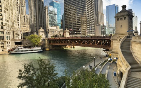 view to a bridge with a boat parked on a side and the city buildings