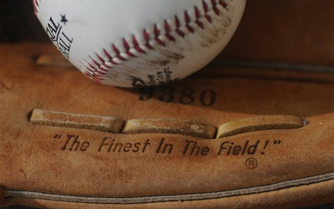 a baseball glove with the word the finest in the field and a baseball 