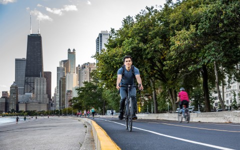 man riding a bicycle on the city and with the buildings in the background