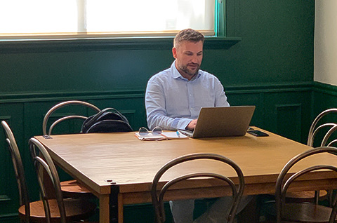 man sitting down while looking at his laptop on a table