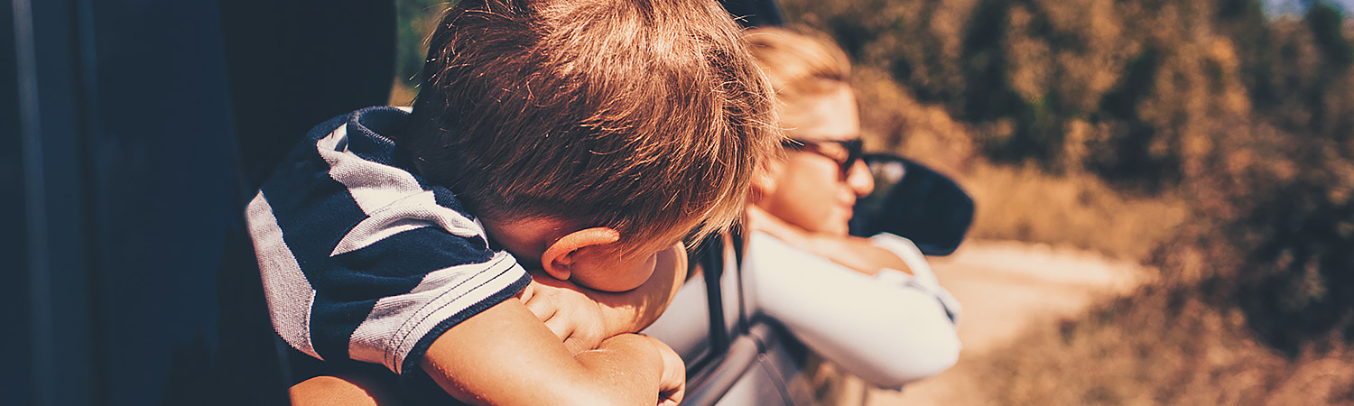 children leaning out of the car window on a road trip