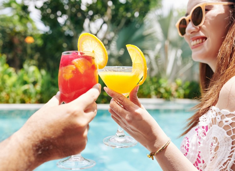couple toasting with tropical drinks outside by pool