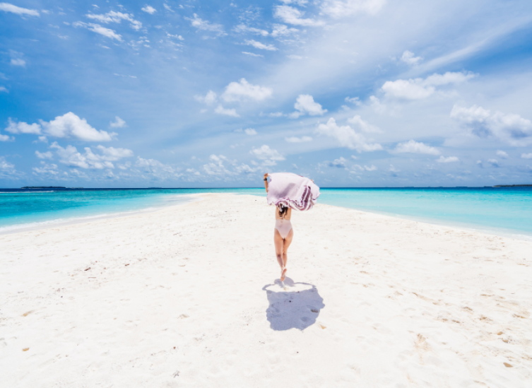 women running down a sandbar holding a towel over her head