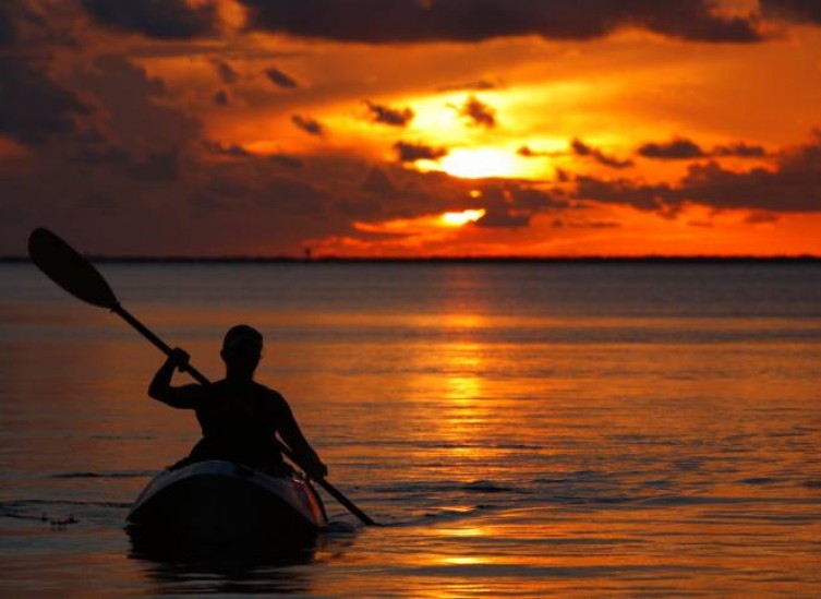 person kayaking in the ocean at sunset